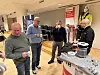 Fire menn snakker ved en Würth-stand med verneutstyr og produkter i en konferansesal.