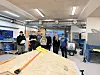 Elever i verksted står bak en tredetallkonstruksjon omgitt av verktøy og maskiner.