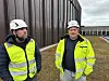 To arbeidere i verneklær og hjelm står utenfor et industribygg.