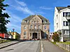 Brosteinsgate med historisk murbygning i sentrum, omgitt av bolighus og trær.