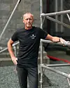 Rune Langås i svart NDR-skjorte står foran et stillas.
