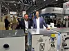 To personer ved industrielt utstyr på en fagmesse.